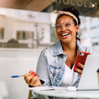 Woman smiling with phone and computer. 