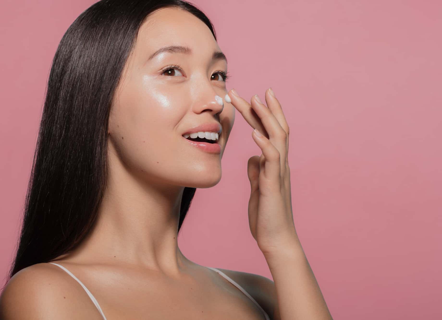 Woman applying cream to her nose. 